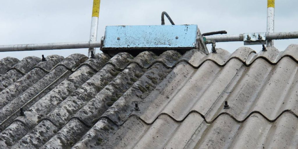 An image showing a roof constructed from corrugated asbestos sheeting, with its characteristic grey color and textured surface