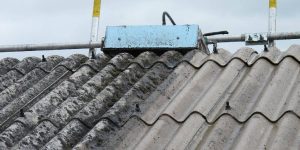 An image showing a roof constructed from corrugated asbestos sheeting, with its characteristic grey color and textured surface. This needs an asbestos removal ASAP