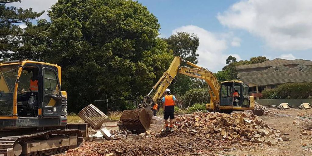 Members of a commercial demolition company from Newcastle in action at a job site, carefully dismantling structures while adhering to safety protocols.