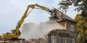 An excavator in action, performing a bare demolition of a structure. 