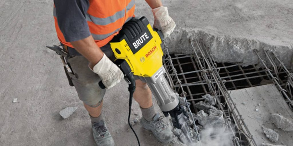 Skilled demolition worker breaking concrete with a powerful jackhammer