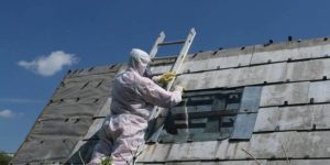 Demolition worker clearing asbestos-filled roof using durable fibre cement."