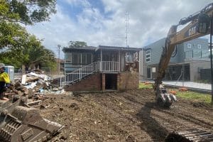 Excavator actively demolishing a residential building in an Australian suburb